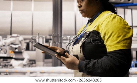 Engineer in smart solar manufacturing facility calibrating high tech machinery and analyzing sensor data. Engineer troubleshooting photovoltaic assembly equipment, camera A close up