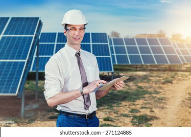 Engineer At Solar Power Station With Solar Panel Tablet Checks. Practical Lessons On Renewable Energy Power Plants.