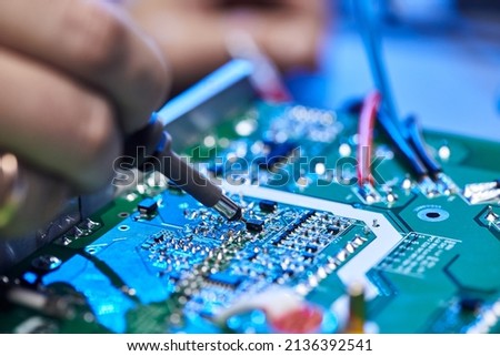 Engineer is soldering a computer board, circuit, chip or microchip. Repairing Hardware Equipment. Repair Shop and Worker with Tools. Testing Modern Digital Device on Desk . Electronic Devices Concept