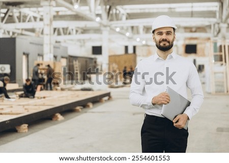 Engineer supervising construction of a modular building in a factory, showcasing innovation and technology. Quality and efficiency ensured indoors