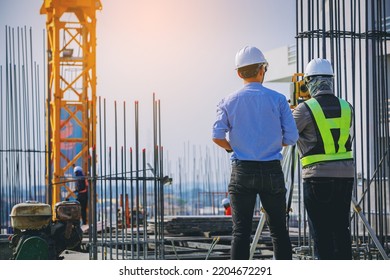 Engineer And Surveyor Worker Working With Theodolite Transit Equipment At Outdoors Construction Site.