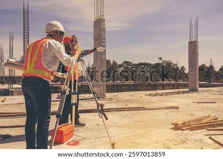 Engineer and surveyor worker working with theodolite transit equipment at outdoors construction site.