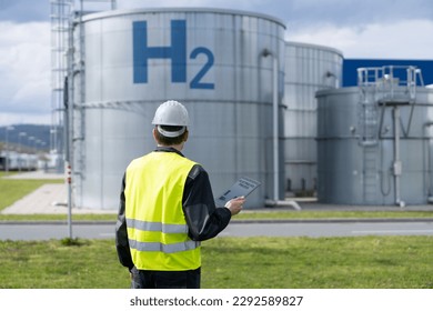 Engineer with tablet computer on a background of Hydrogen factory - Powered by Shutterstock