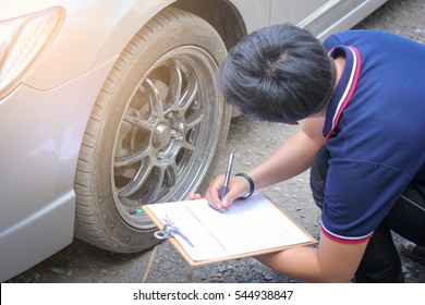 Engineer taking notes on a clipboard for vehicle inspection.
