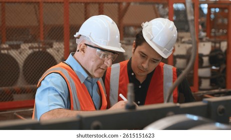 Engineer teaching apprentice to use metal sheet stamping machine, industrial team is working on various projects with tablet computer, worker work together to check the operation system in a factory