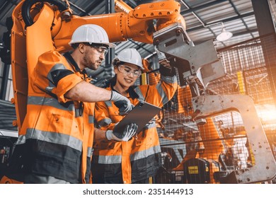 Engineer team service robot welding working in automation factory. People worker in safety suit work robotic arm software programming or replacing part in automated manufacturing industry technology. - Powered by Shutterstock