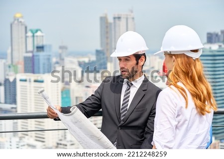 Engineer team are working to look at blueprint paper on rooftop building with cityscape view background , Enggirneer Rooftop Concept.