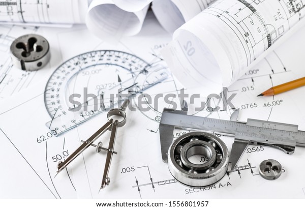 Engineer\
technicial drawings and  mechanical parts engineering industry work\
project paper prints. Measuring tools on\
table.
