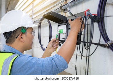 Engineer or technician checking fiber optic cables in internet splitter box.Fiber to the home equipment. FTTH internet fiber optics cables and cabinet. - Shutterstock ID 2030176718