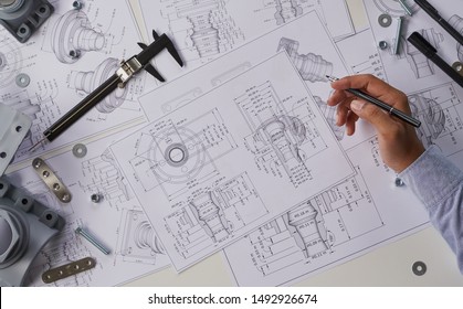 エンジニア技術者が機械部品工学エンジンの図面を設計する製造工場産業産業プロジェクトの青写真で、キャリパー工具を測定