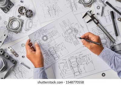 Engineer technician designing drawings mechanical parts engineering Engine
manufacturing factory Industry Industrial work project blueprints measuring bearings caliper tools                           