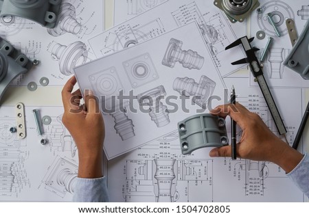 Engineer technician designing drawings mechanical parts engineering Engine
manufacturing factory Industry Industrial work project blueprints measuring bearings caliper tools
