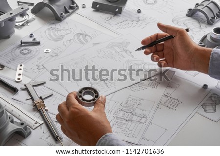 Engineer technician designing drawings mechanical parts engineering Engine
manufacturing factory Industry Industrial work project blueprints measuring bearings caliper tools 