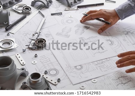 Engineer technician designing drawings mechanical parts engineering Engine
manufacturing factory Industry Industrial work project blueprints measuring bearings caliper tool.