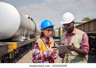 An Engineer Or Technician, A Freight Train Maintenance Specialist, Stands Holding A Tablet And Is Discussing Outdoor Maintenance Work.