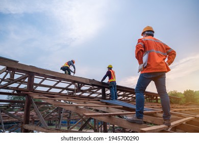 Engineer Technician Watching Team Of Roofer Working On Roof Structure Of Building In Construction Site, Roof Metal Sheet Construction Concept.