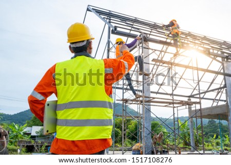Engineer technician watching team of workers on high steel platform,Engineer technician Looking Up and Analyzing an Unfinished Construction Project at Worksite on construction site.