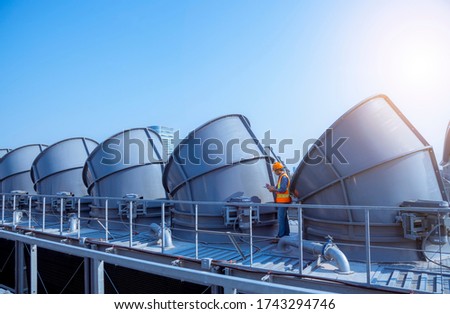 A engineer under checking the industry cooling tower air conditioner is water cooling tower air chiller HVAC of large industrial building to control air system.