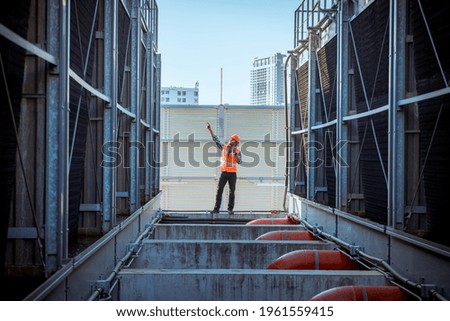Engineer under checking the industry cooling tower air conditioner is water condenser cooling tower air chiller HVAC of large industrial building to control air system.