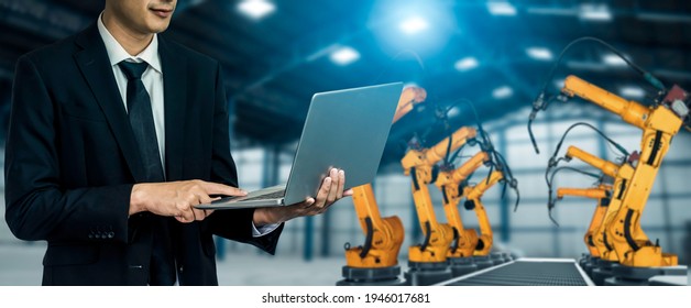 Engineer use advanced robotic software to control industry robot arm in factory . Automation manufacturing process controlled by specialist using IOT software connected to internet network . - Shutterstock ID 1946017681