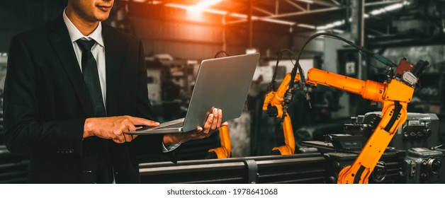 Engineer Use Advanced Robotic Software To Control Industry Robot Arm In Factory . Automation Manufacturing Process Controlled By Specialist Using IOT Software Connected To Internet Network .