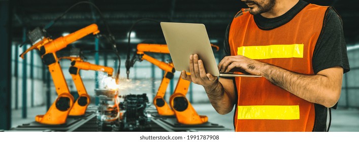 Engineer Use Advanced Robotic Software To Control Industry Robot Arm In Factory . Automation Manufacturing Process Controlled By Specialist Using IOT Software Connected To Internet Network .