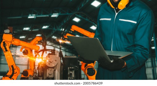 Engineer Use Advanced Robotic Software To Control Industry Robot Arm In Factory . Automation Manufacturing Process Controlled By Specialist Using IOT Software Connected To Internet Network .