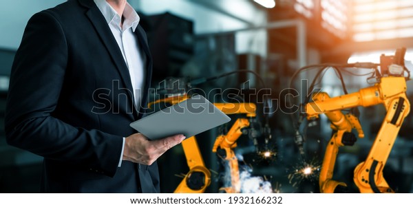 Engineer use advanced robotic software to control
industry robot arm in factory . Automation manufacturing process
controlled by specialist using IOT software connected to internet
network .