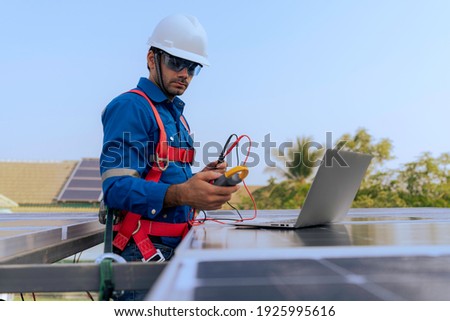 An Engineer use a laptop computer to examine, inspection the solar panels at roof top of home and home office ,concept of economic energy and cost saving
