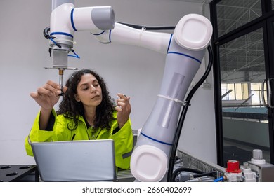 Engineer uses robotic arm for precise component assembly in modern tech lab during daytime