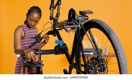 Engineer uses screwdriver to tighten brake levers screws on bicycle handlebars, examining components, studio background. Expert unscrewing defective bike parts in order to recondition them, studio B - Powered by Shutterstock