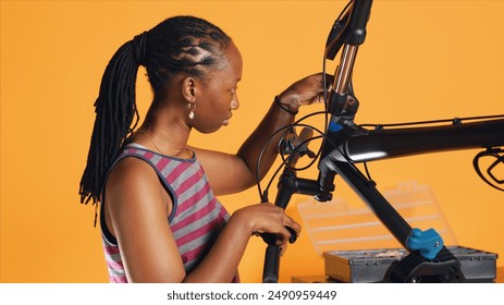 Engineer uses screwdriver to tighten brake levers screws on bicycle handlebars, examining components, studio background. Expert unscrewing defective bike parts in order to recondition them, studio A - Powered by Shutterstock