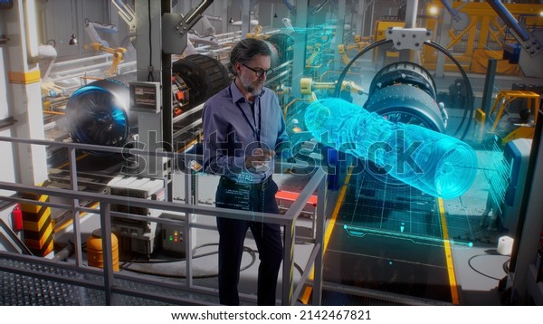 An engineer uses a tablet with a holographic\
innovative application, to model and design and monitor a 3D model\
of an aircraft engine while on an automated robotic line at an\
aerospace factory