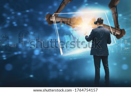 Engineer using augmented reality technology with wearing VR goggles,control system of city with robot arm,with monitoring system control interface screen display,with smart city holographic.