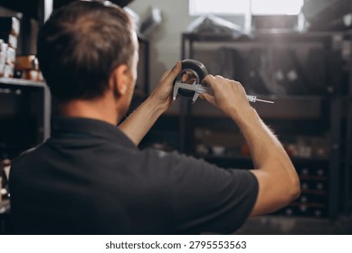 Engineer using a caliper to measure a metal component, ensuring precision and quality control in a workshop environment