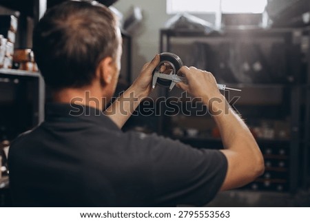 Engineer using a caliper to measure a metal component, ensuring precision and quality control in a workshop environment