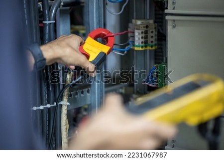 An engineer is using a clamp meter to measure an electric current.