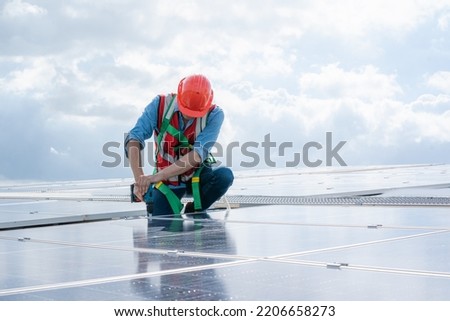 Engineer using dril installing solar cell on roof factory,Environment friendly,Alternative energy to conserve the world's energy.