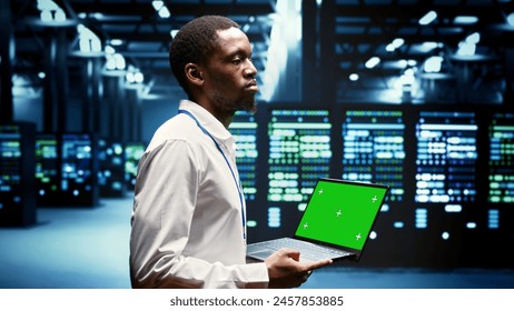 Engineer using green screen laptop to do maintenance on high bandwidth, dedicated game servers used to accommodate incoming traffic of online users joining from worldwide locations.