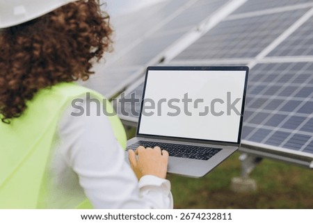 Engineer using laptop with blank screen in a solar power station, checking and controlling production