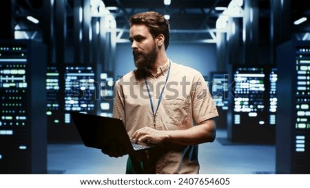Engineer using laptop to monitor energy consumption across server components and distributors. Expert ensuring data center sensors for temperature and humidity are functioning optimally