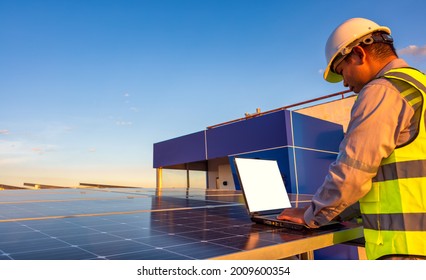 Engineer using laptop at solar panels on rooftop at sunset sky, An engineer working at a photovoltaic farm. Eco technology for electric power