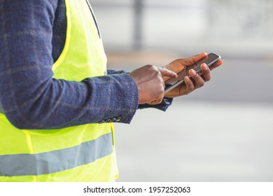 Engineer Using A Mobile App. Engineer, Architect Or Supervisor In Front Of A New Office Building, Holding Plans And Using A Mobile App. Foreman Sending Instructions Via Smartphone