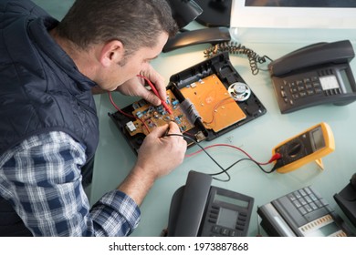 Engineer Using Multimeter To Test A Telephone