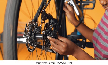 Engineer using screwdriver and hex socket wrench to secure wheel on bicycle in studio background, professional screwing bolts on bike parts, mending rear derailleur and cassette.