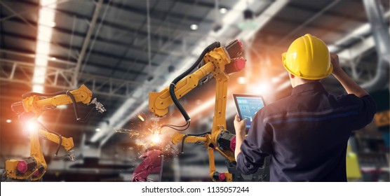 Engineer using tablet check and control automation robot arms machine in intelligent factory industrial on monitoring system software. Welding robotics and digital manufacturing operation.  - Shutterstock ID 1135057244