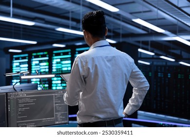 Engineer using tablet to troubleshoot hardware and software issues in server hub. IT specialist implementing and maintaining server and network infrastructure in data center