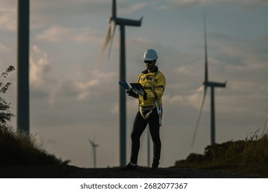Engineer using tablet at wind farm during sunset, representing smart energy monitoring, digital inspection, and commitment to renewable power and sustainable development in clean technology.