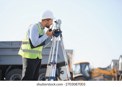 Engineer using a total station instrument and radio, working on site infrastructure development. Measuring land for construction