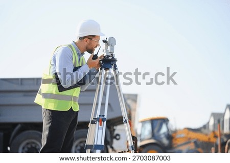 Engineer using a total station instrument and radio, working on site infrastructure development. Measuring land for construction